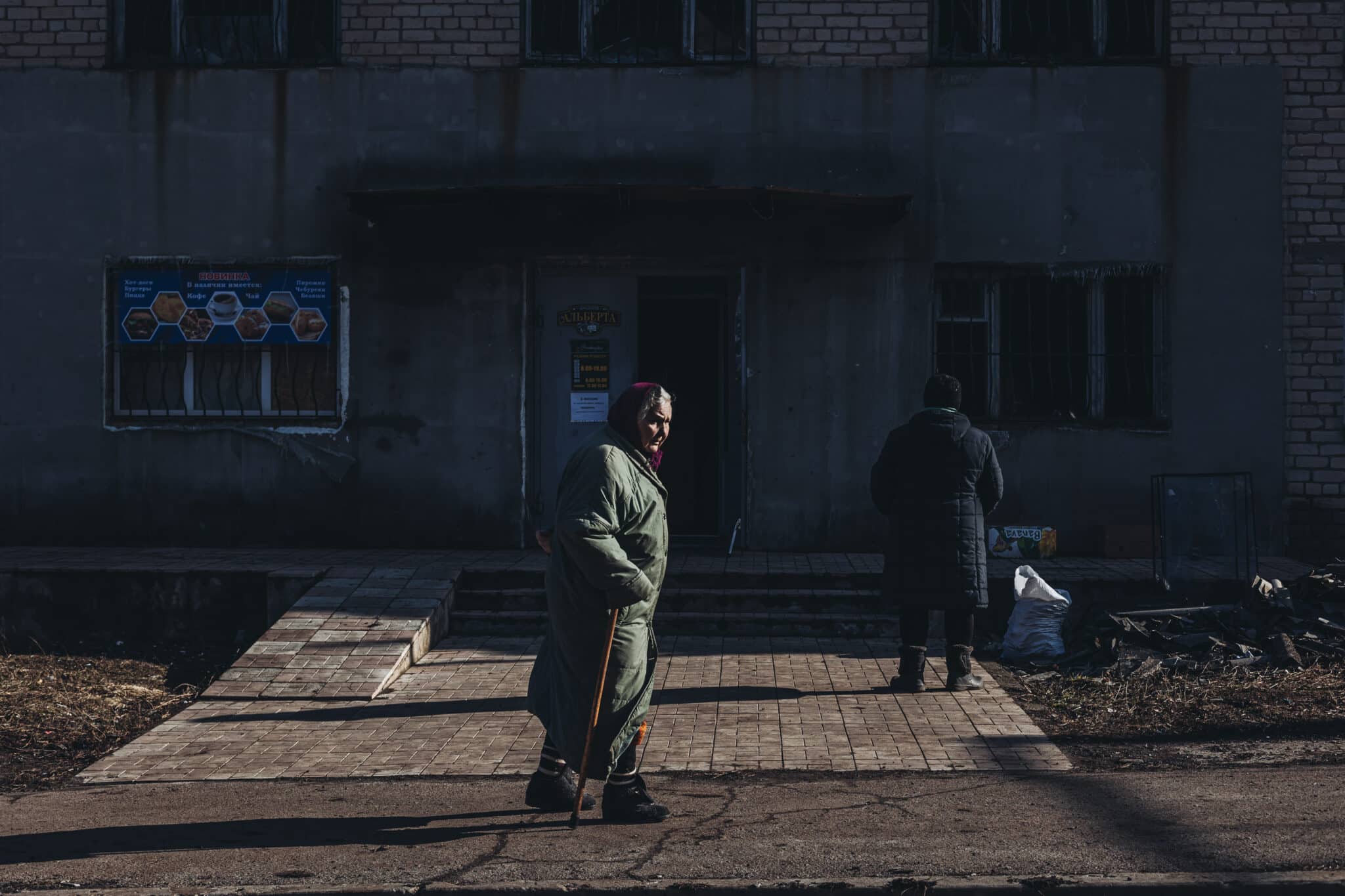 Una mujer mayor camina frente a un edificio bombardeado, en Novoluhans'ke, Oblast de Donetsk (Ucrania)