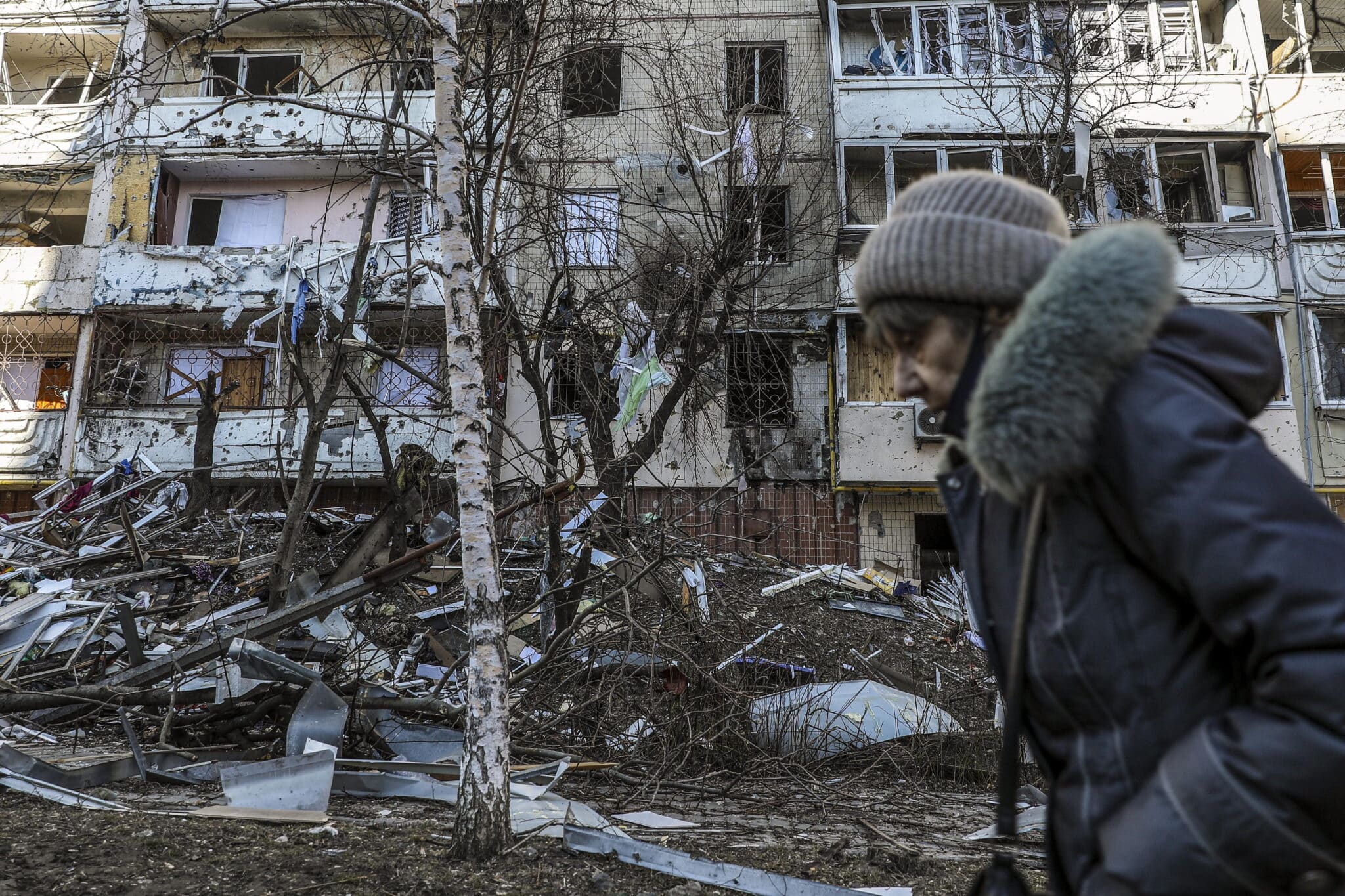 Una mujer pasa junto a los escombros de un edificio dañado por los bombardeos en Kiev.