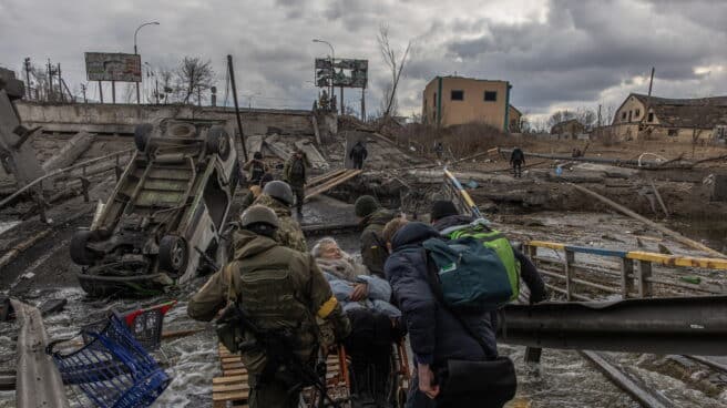 Soldados ucranianos ayudan a un anciana en Irpin, cerca de Kiev