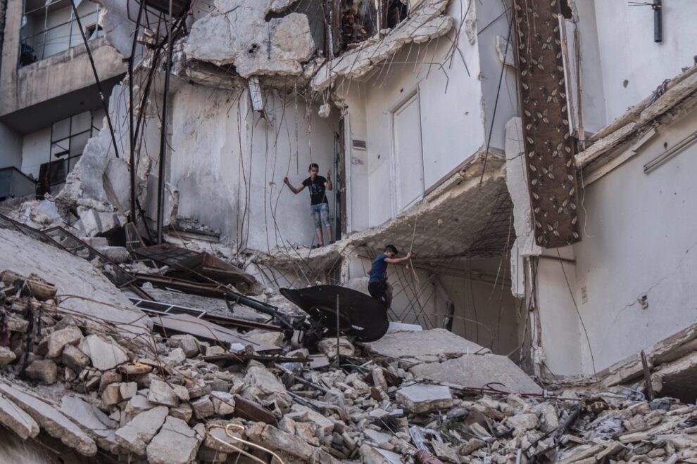 Unos menores sirios entre los escombros de un edificio en Alepo.