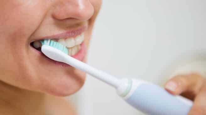 Mujer cepillándose los dientes con un cepillo eléctrico