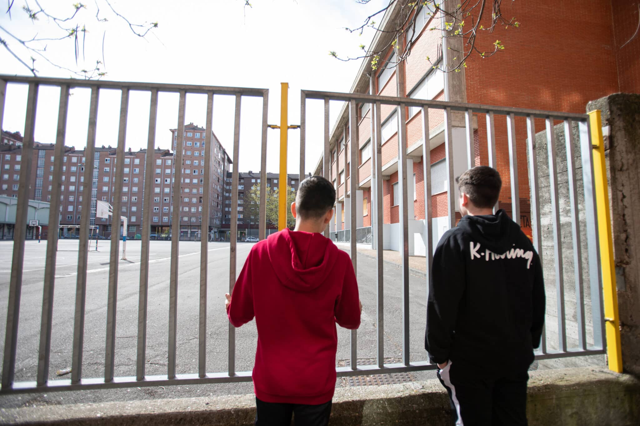 Dos adolescentes observan el patio cerrado de un colegio durante el confinamiento en 2020.