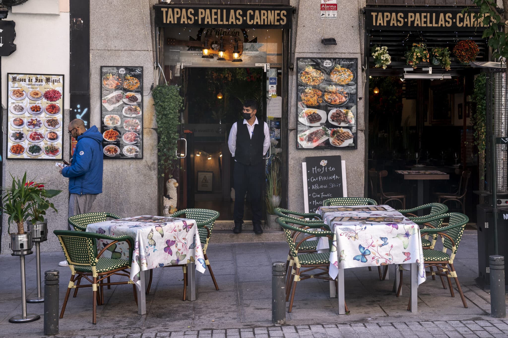 Un camarero delante de una terraza de un restaurante de Madrid.