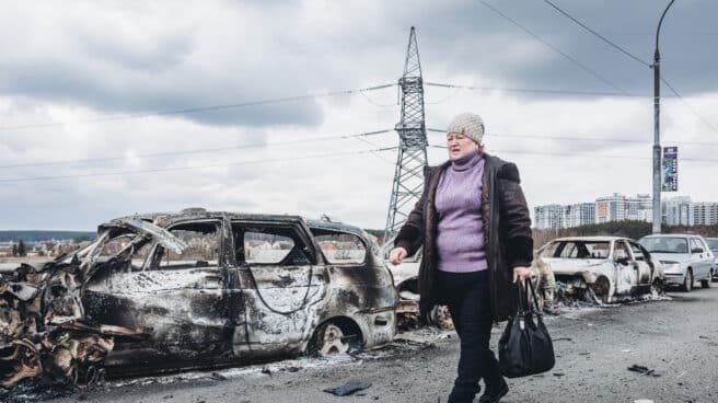 Rusia y Ucrania acuerdan un alto al fuego de 12 horas para abrir corredores humanitarios Una mujer camina delante de unos coches quemados en un puente de Irpin (Ucrania)