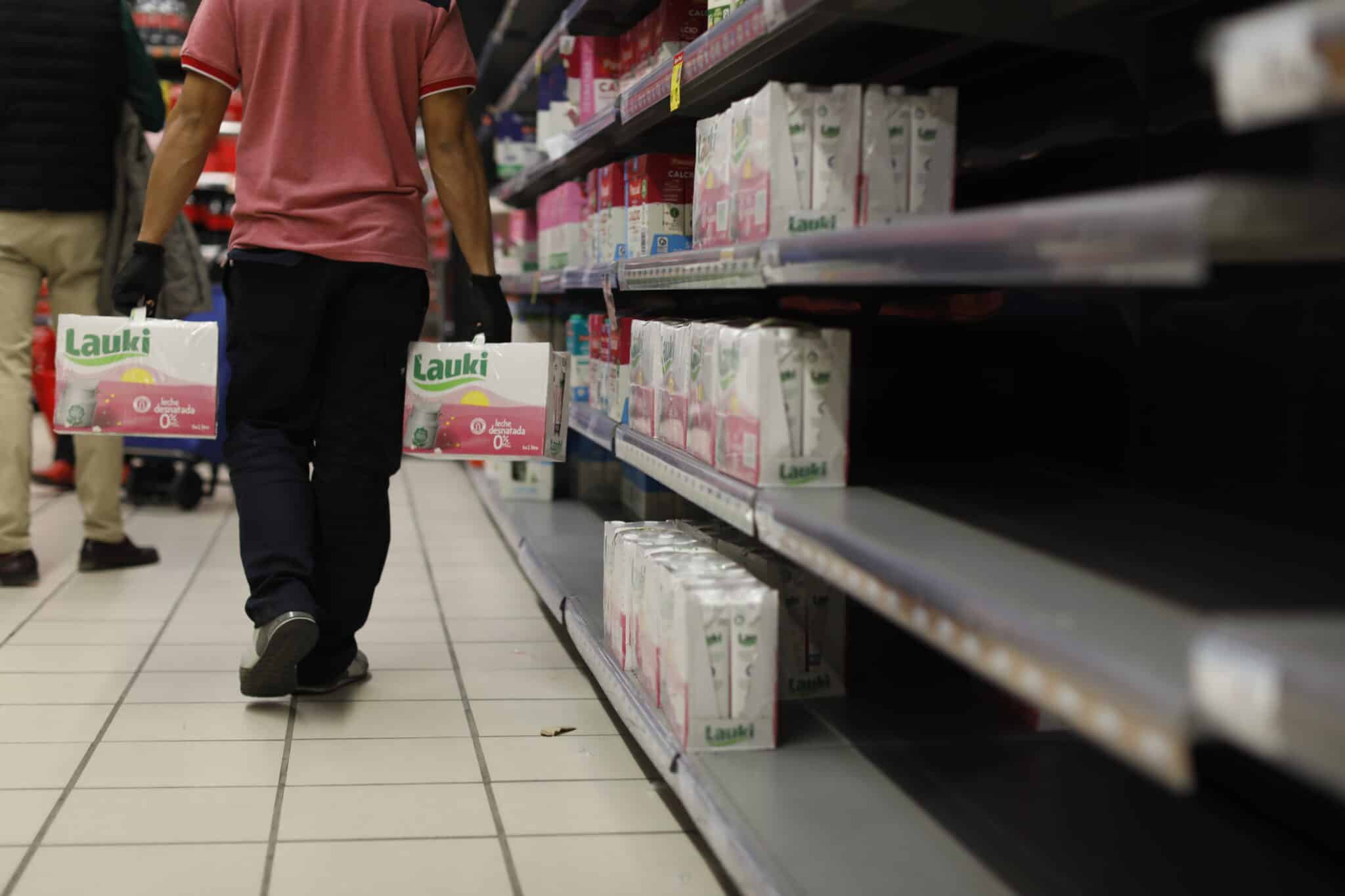Un reponedor con cajas de leche en un supermercado de Madrid.
