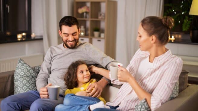 Las tazas más originales para regalar en este Día del padre Hombre niña y mujer sentados en un sofá con tazas en la mano