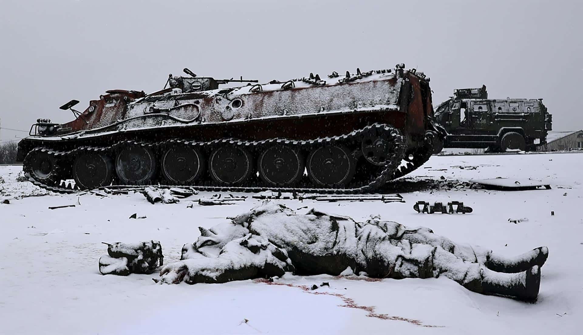 Un soldado yace muerto junto a un tanque ruso quemado.