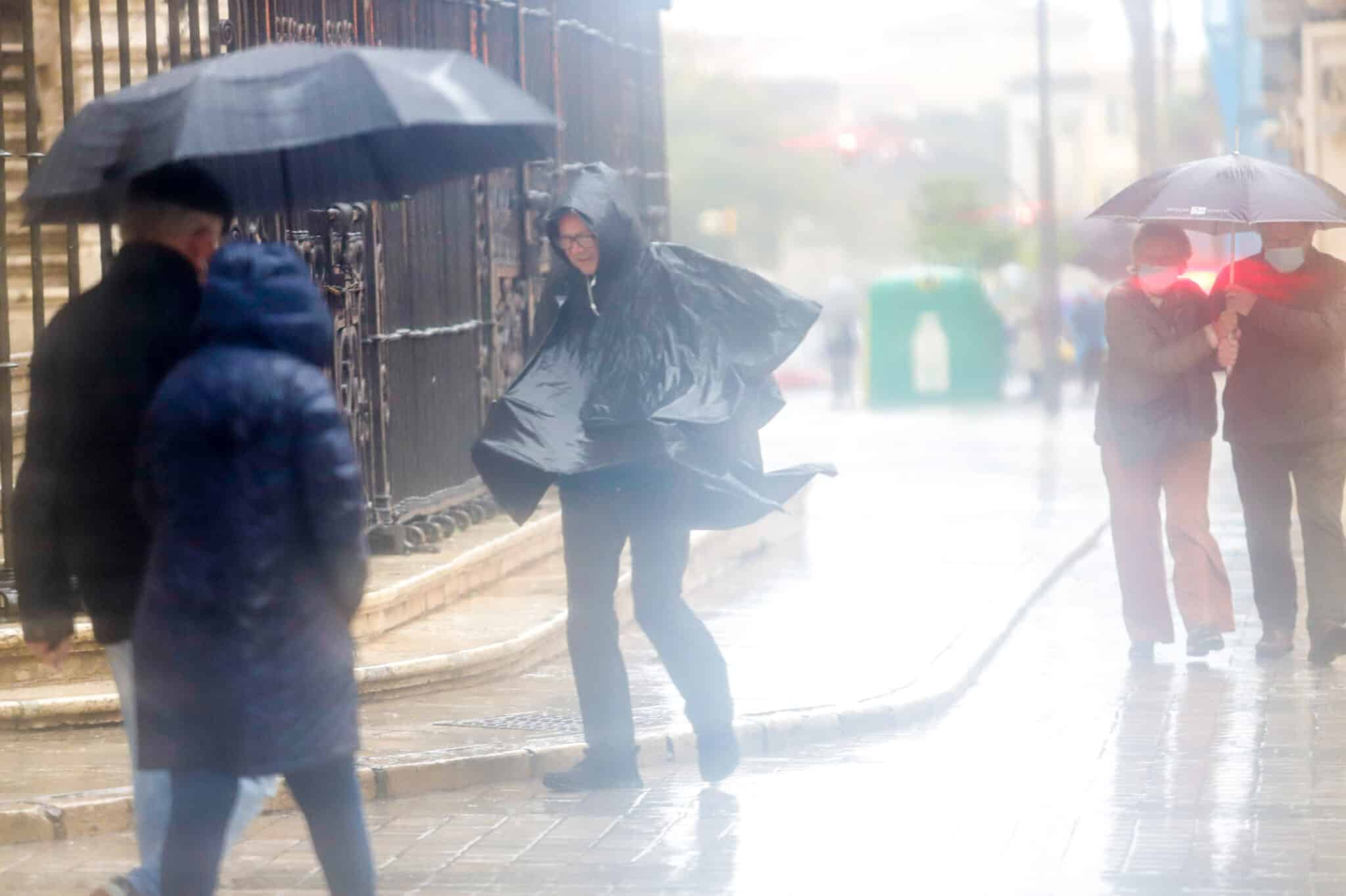 Gente anda por la calle en Málaga mientras llueve intensamente.