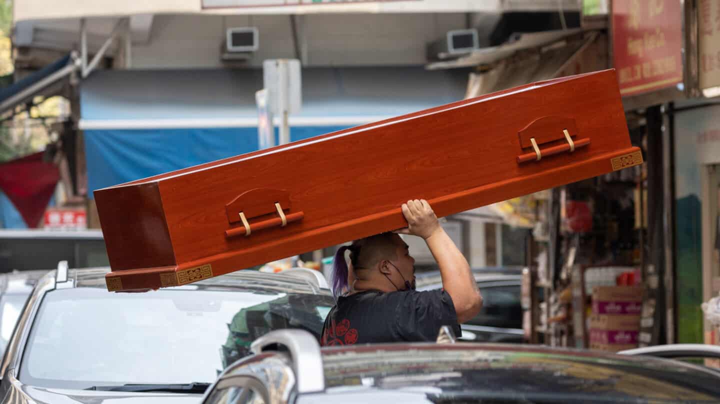 Un hombre carga un ataúd en Hong Kong, que vive su peor ola de la pandemia con una gran mortalidad.