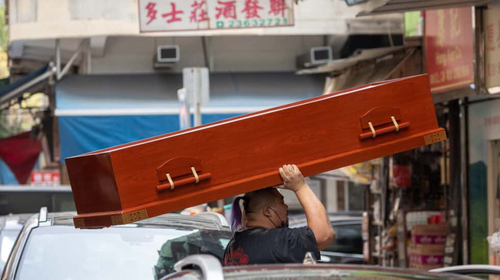 Un hombre carga un ataúd en Hong Kong, que vive su peor ola de la pandemia con una gran mortalidad.