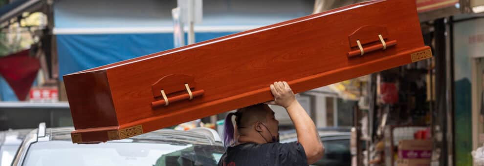 Un hombre carga un ataúd en Hong Kong, que vive su peor ola de la pandemia con una gran mortalidad.