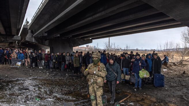 Civiles esperan para salir de Irpin, cerca de Kiev, junto a un soldado del ejército de Ucrania.