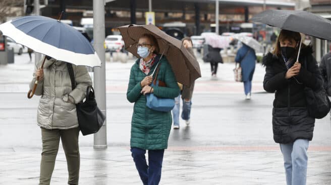Tres mujeres pasean con paraguas por el centro de Madrid