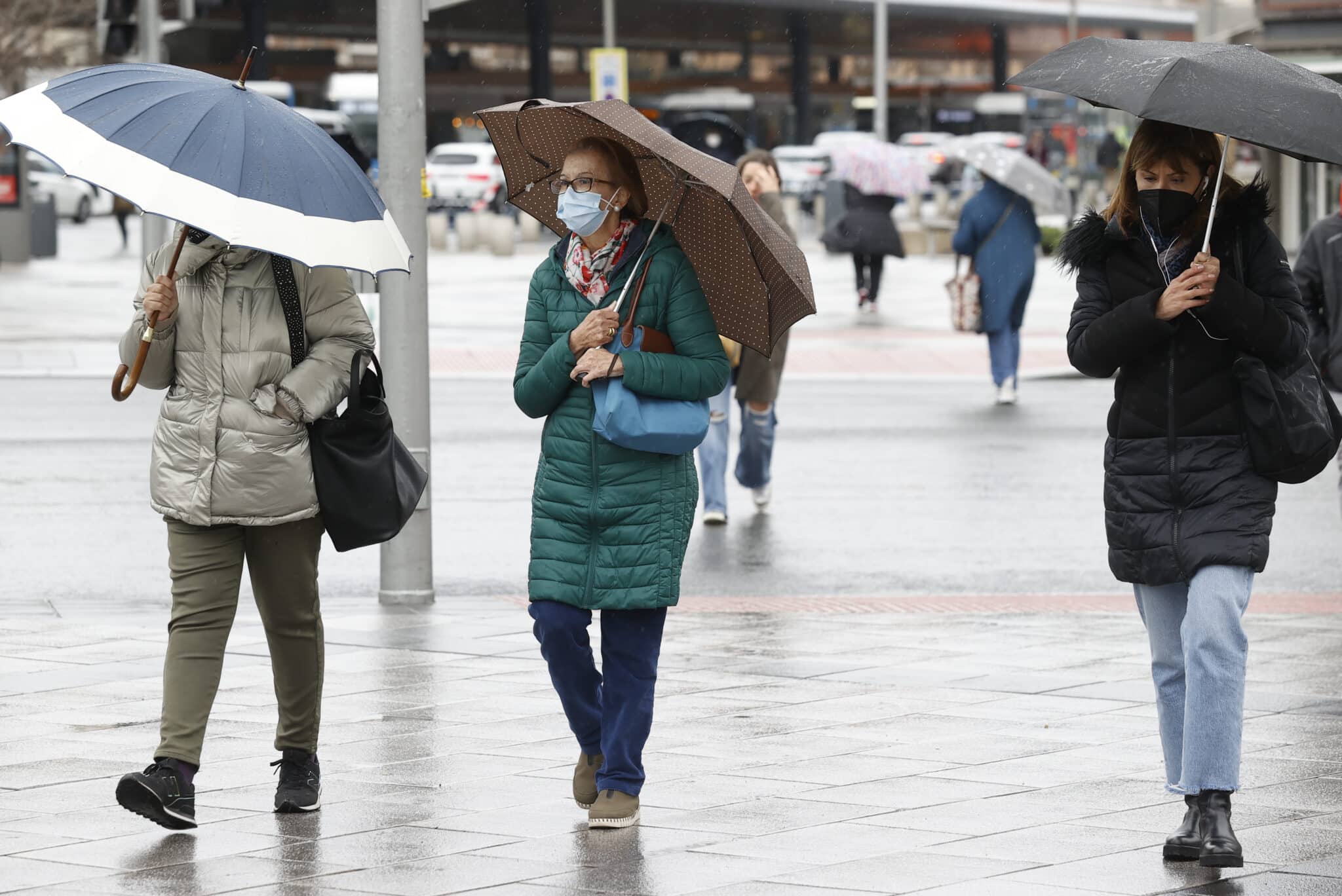 Tres mujeres pasean con paraguas por el centro de Madrid