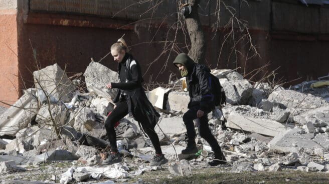 Dos jóvenes ucranianos caminan sobre los restos de un edificio destruido en Mariúpol (Ucrania)