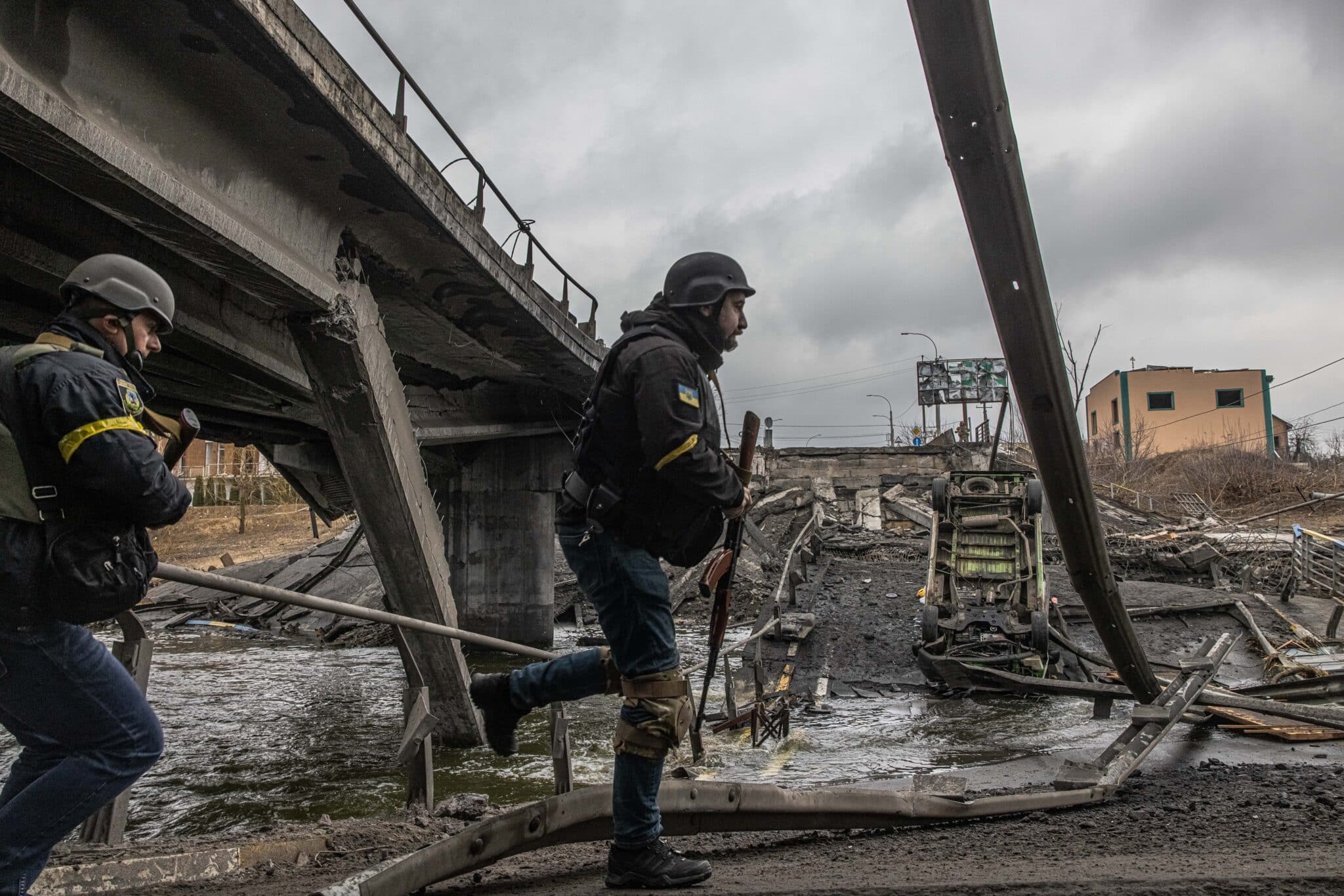 Militares ucranianos corren sobre los restos de un puente destruido en Irpín, al noroeste de Kiev (Ucrania)
