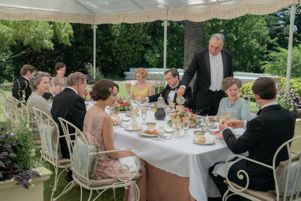 Escena de "Downton Abbey: una nueva era", la película, en la que se ve a los personajes disfrutando de una comida en una terraza llena de vegetación