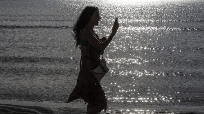 Una mujer habla con su teléfono, que han disparado el uso de datos durante Semana Santa Una mujer pasea durante esta Semana Santa por la playa con su teléfono móvil