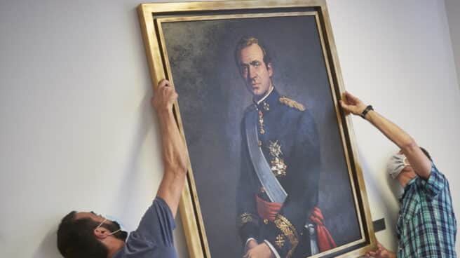 Dos operarios retiran un cuadro de Juan Carlos I.