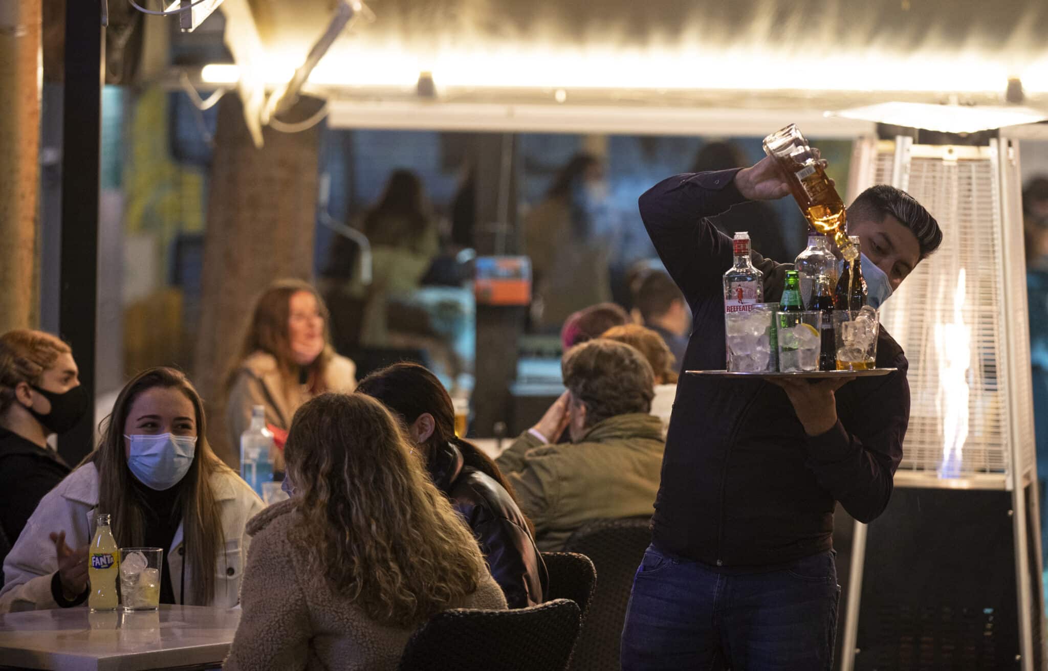 Un camarero sirve alcohol después de las 20h en la terraza de un bar