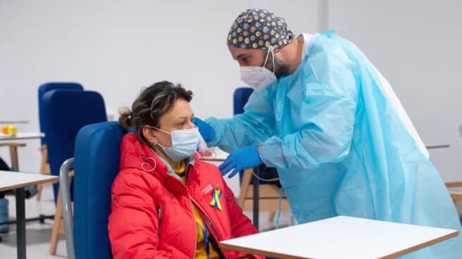 Trabajador sanitario con un refugiado Un trabajador sanitario revisa a una persona procedente de Ucrania en las instalaciones del Hospital Enfermera Isabel Zendal, en Madrid.