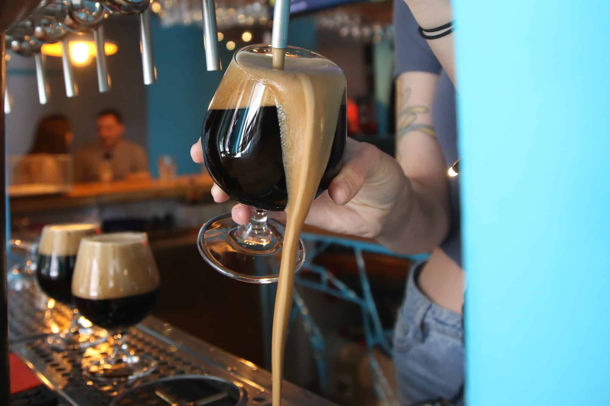 Cerveza negra artesanal siendo servida en la barra de un bar