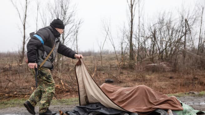 Un soldado ucraniano tapa varios cadáveres en Bucha.