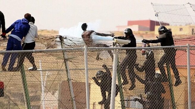 Guardia civiles usan extintores en la valla de Melilla.