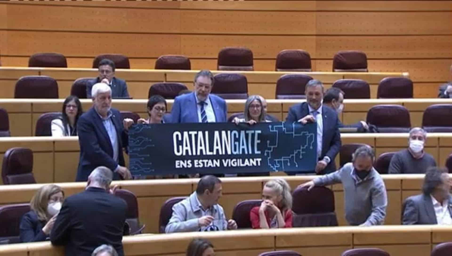 Los senadores de Junts muestran un cartel de 'Catalán Gate, nos están vigilando', en el Pleno del Senado