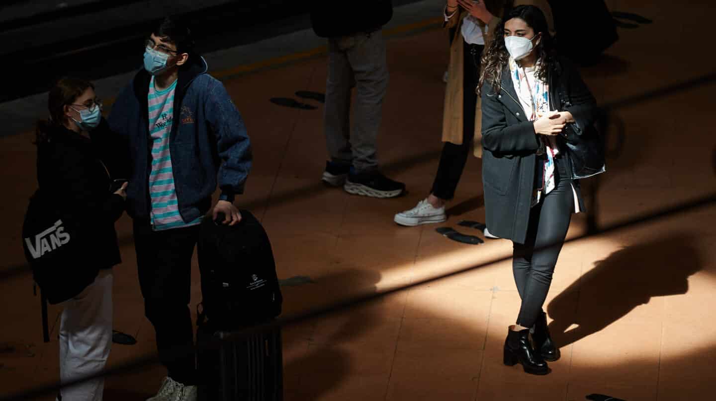 Varias personas con mascarilla esperan en el andén