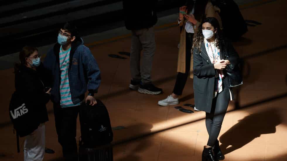 Varias personas con mascarilla esperan en el andén