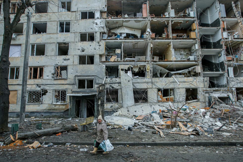 Una mujer pasea cerca de un edificio destruido en Járkov