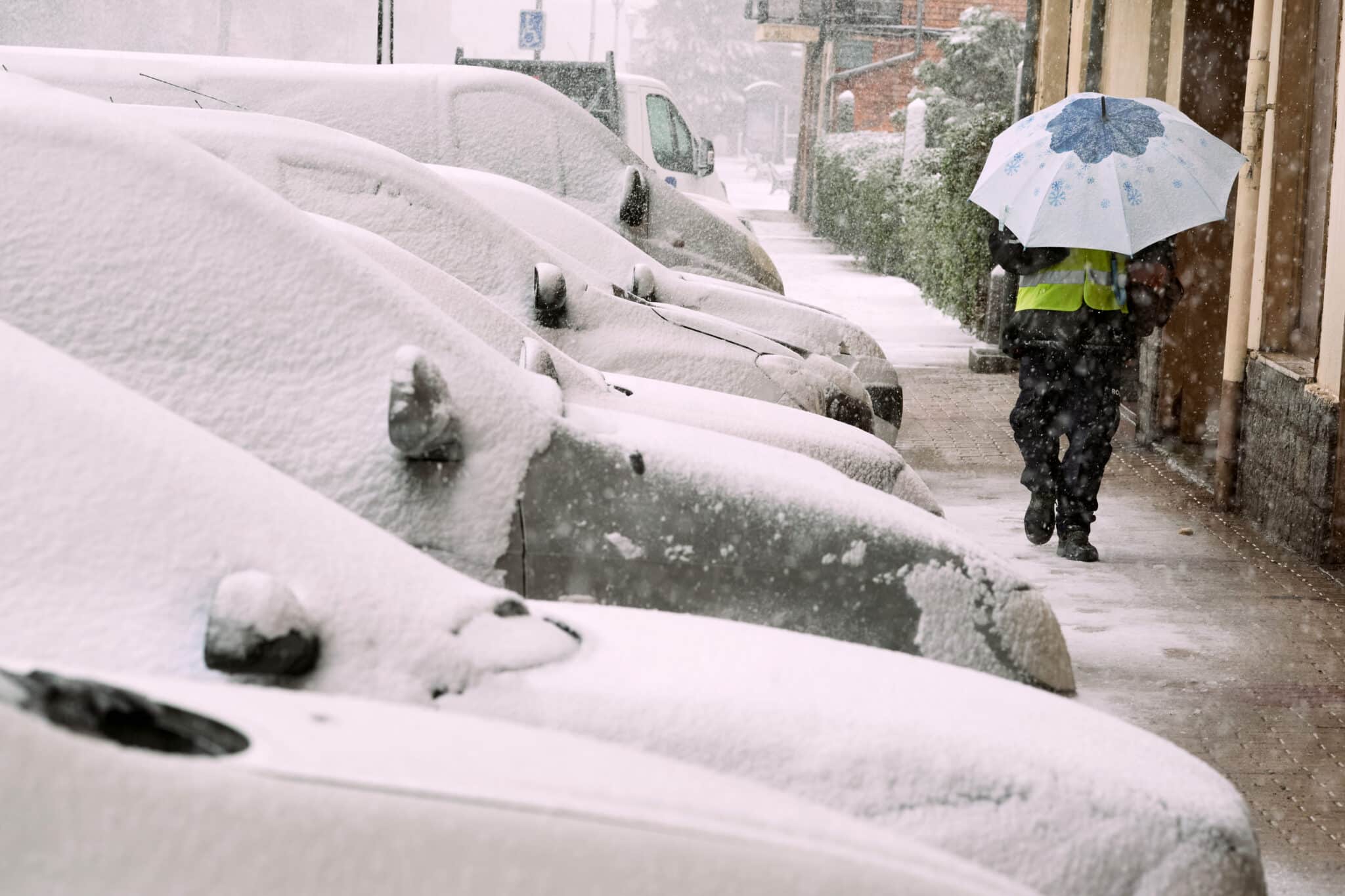 Un hombre se protege de la nieve en las calles de Ávila