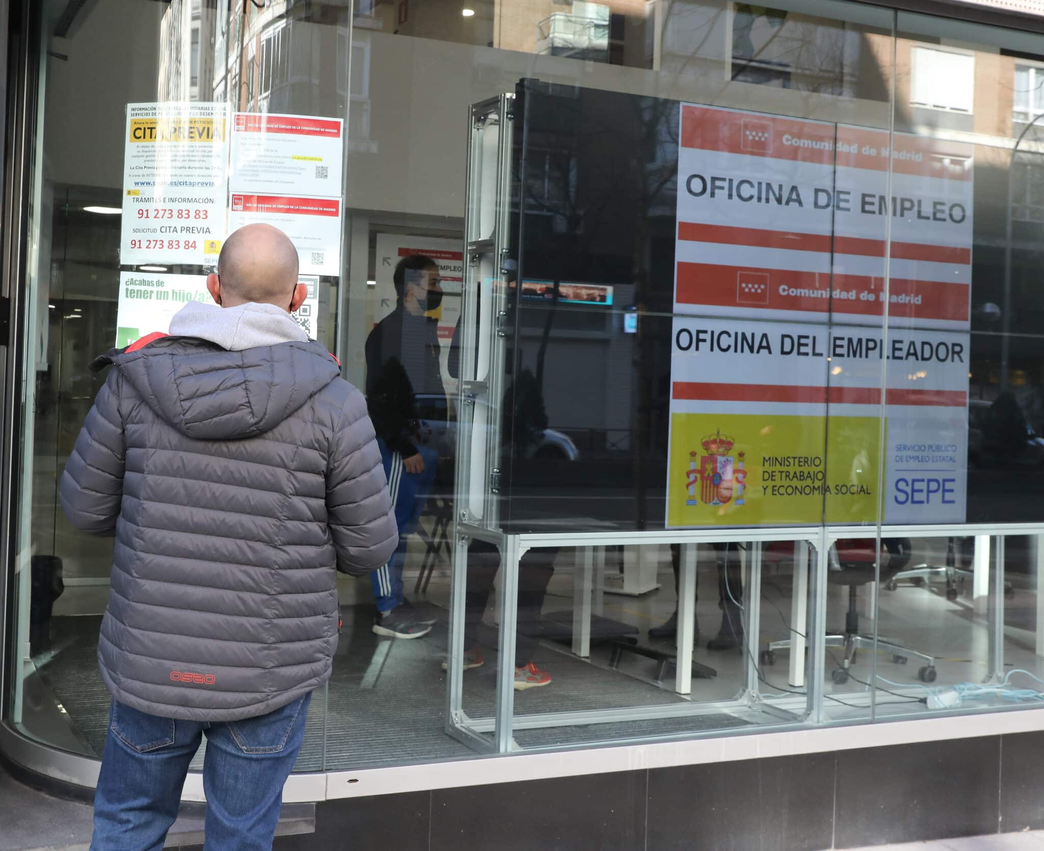 Un hombre observa la cristalera de una oficina de empleo.