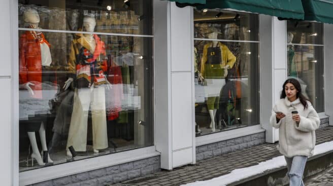 Una mujer pasea al lado de una tienda en Moscú Una mujer pasea al lado de una tienda en Moscú