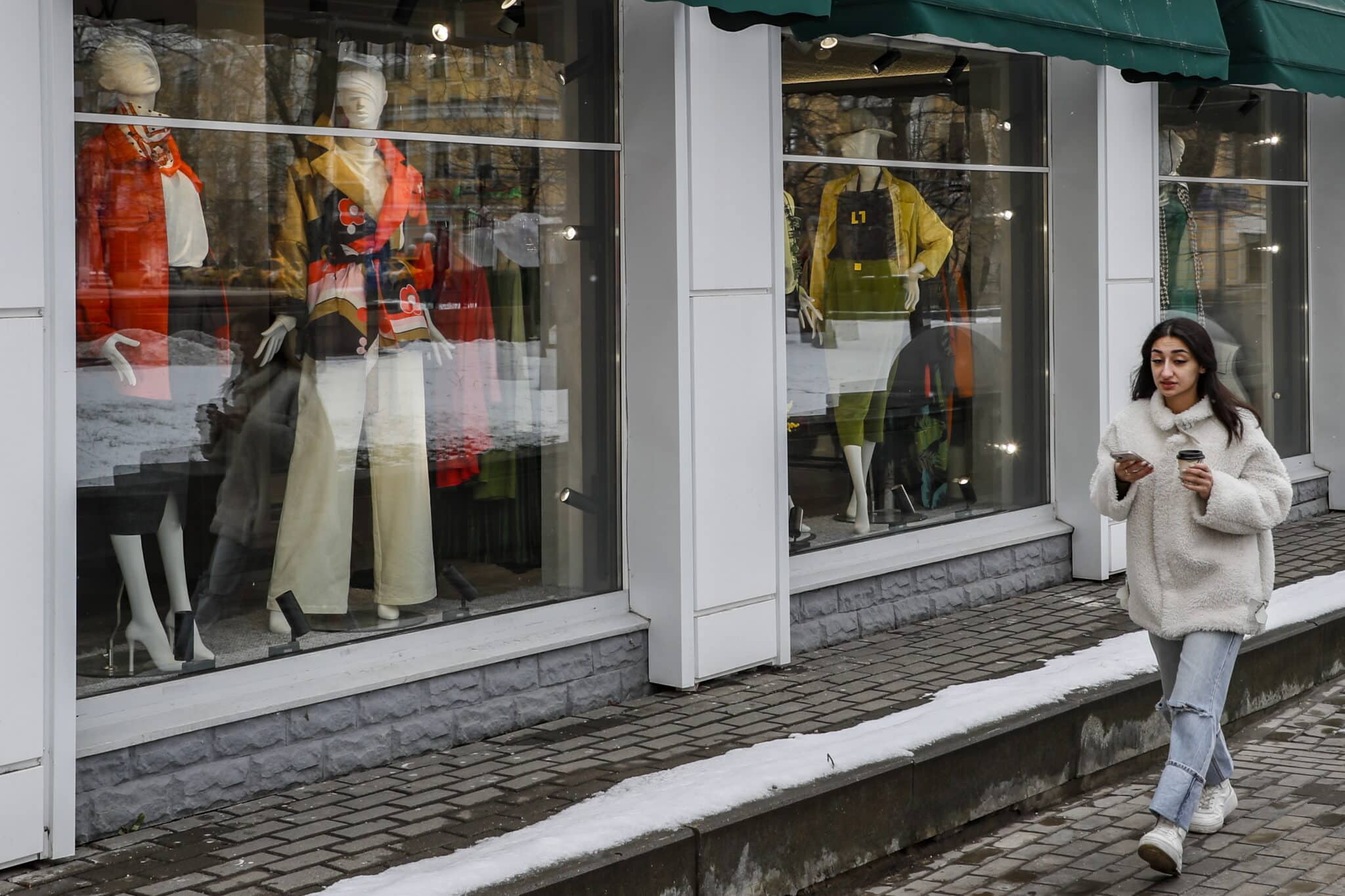 Una mujer pasea al lado de una tienda en Moscú