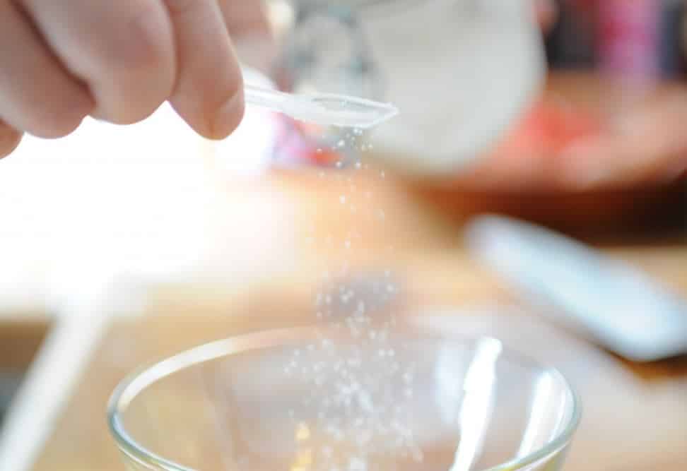 Persona que cocina con sal echando una pizca con una cucharilla