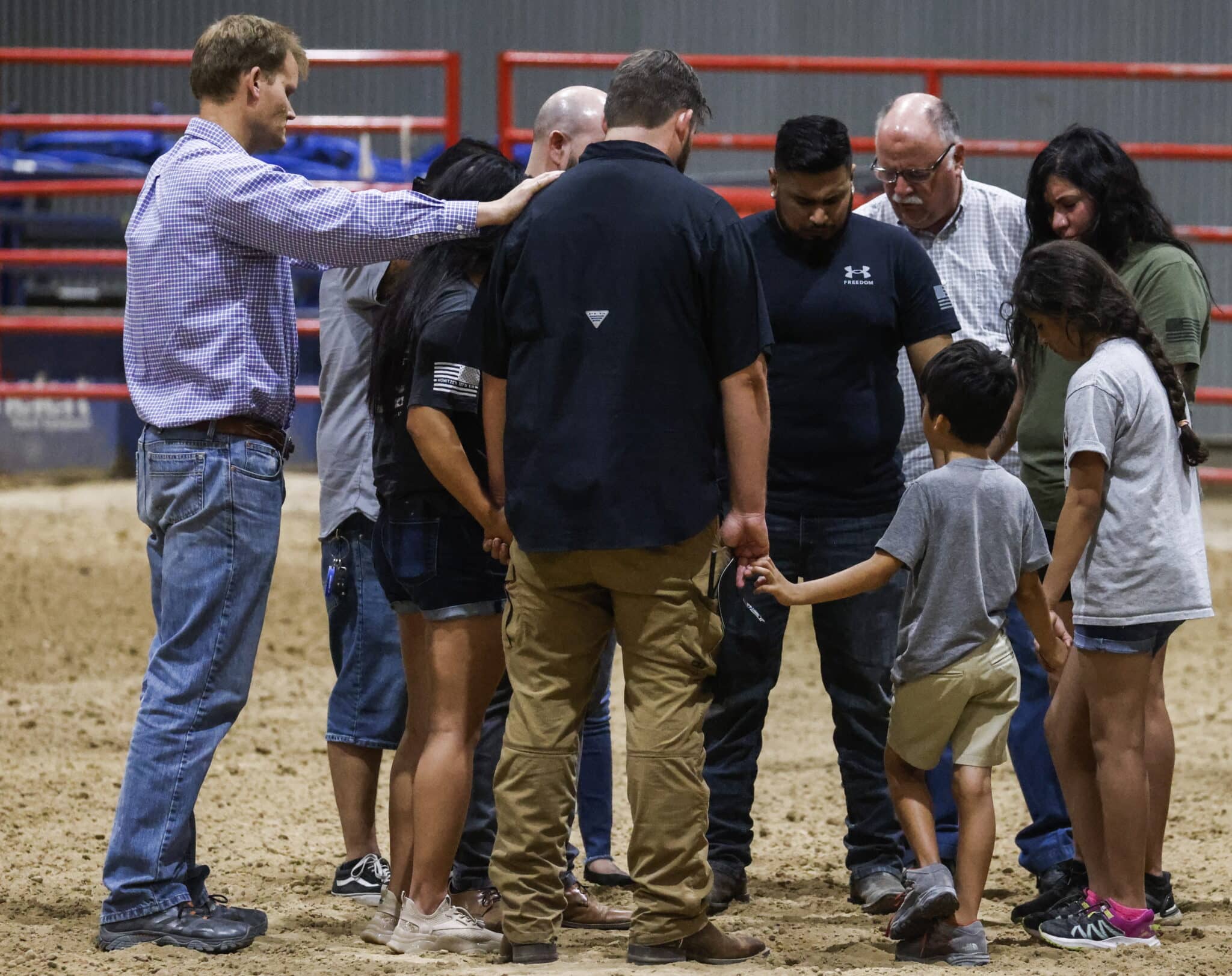 Un grupo de adultos y dos niños rezan de la mano durante la vigilia por el tiroteo en el colegio de Texas