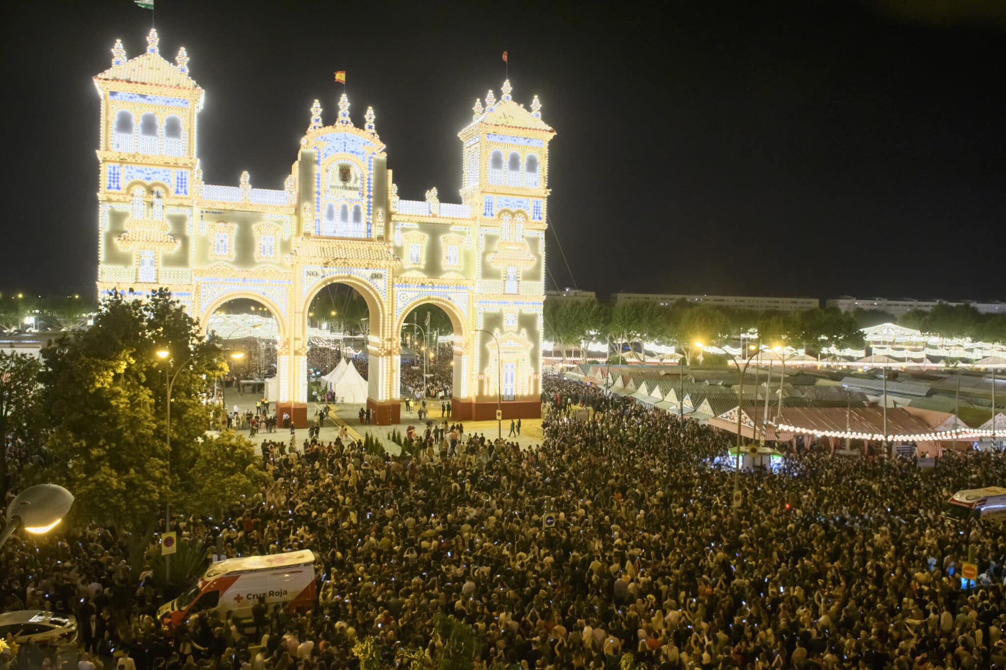 Miles de personas asisten al tradicional "Alumbrao" de las miles de bombillas de la Puerta de la Feria de Abril