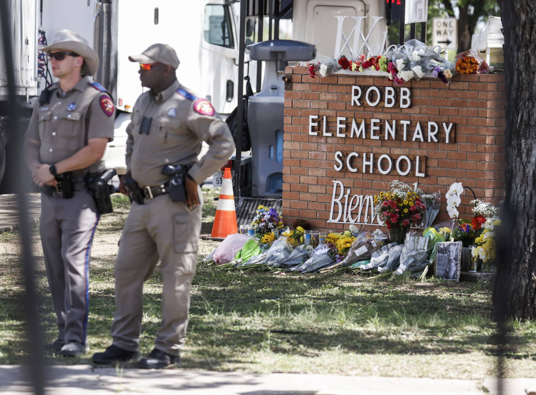 Oficiales de la Patrulla de Carreteras de Texas se paran cerca de un monumento de flores en la escena de un tiroteo masivo en la Escuela Primaria Robb en Uvalde