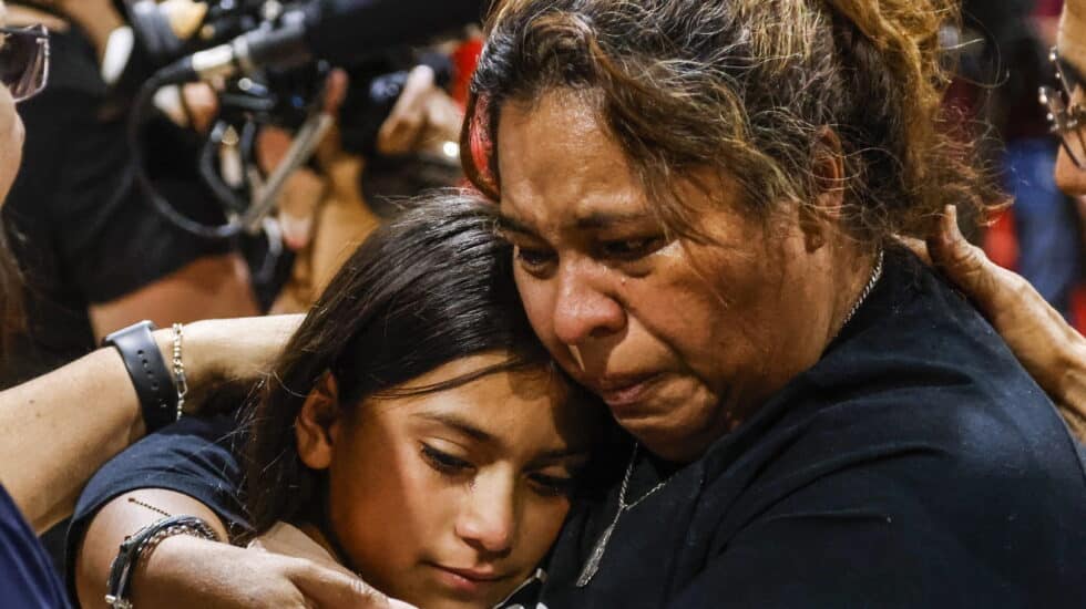 Una mujer y una niña lloran abrazadas durante la vigilia por el tiroteo en Texas