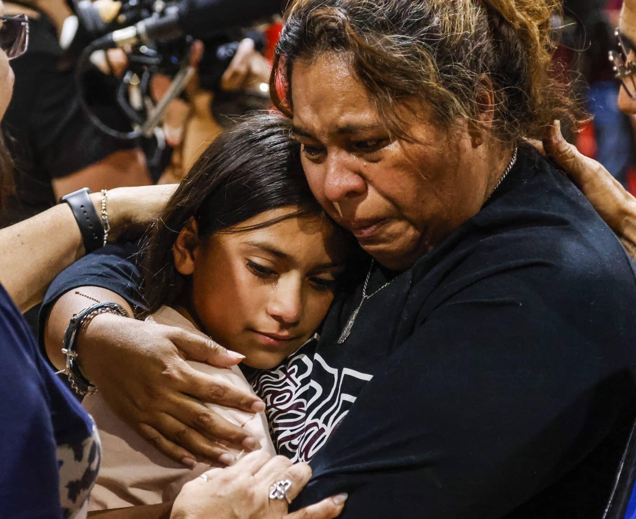 Una mujer y una niña lloran abrazadas durante la vigilia por el tiroteo en Texas