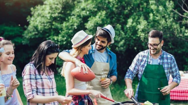 Cinco personas alrededor de una barbacoa mientras los alimentos se cocinas