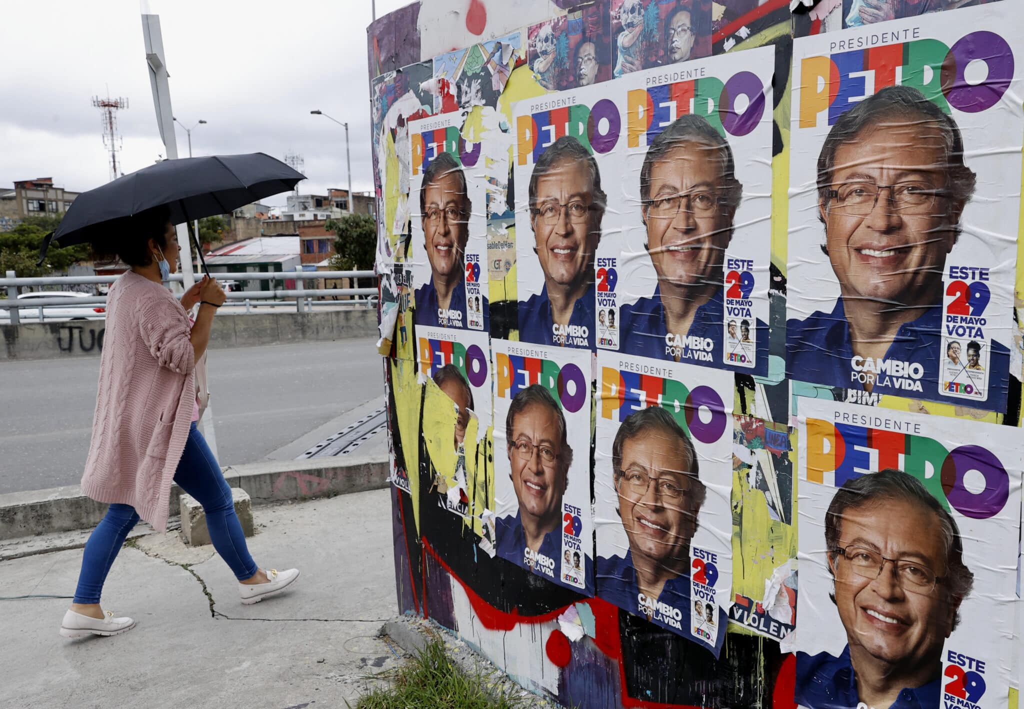 Un mujer pasa cerca de varios carteles con la imagen de Petro