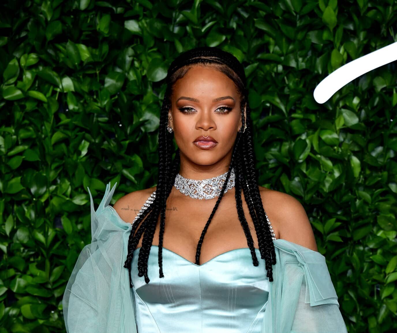 Rihanna en Londres con un vestido azul, delante de un fondo con vegetación verde