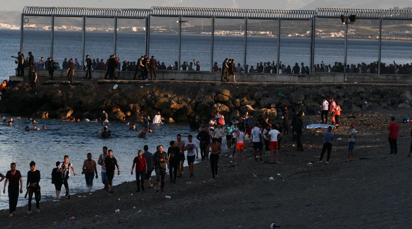 Decenas de migrantes caminan por la playa ceutí del Tarajal el 17 de mayo de 2021.