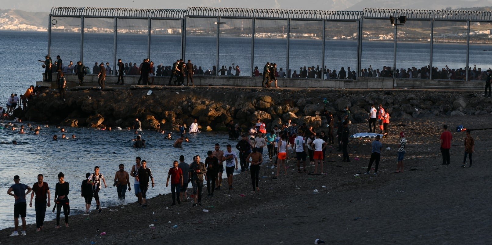 Decenas de migrantes caminan por la playa ceutí del Tarajal