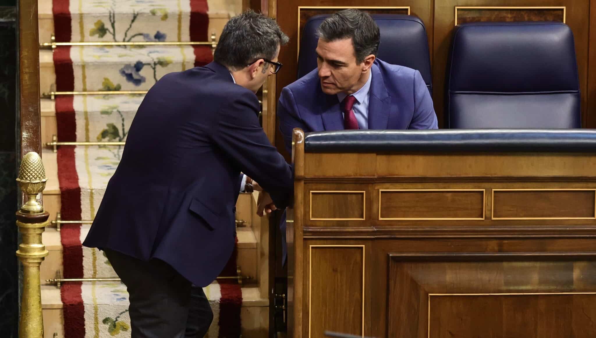 El ministro de la Presidencia, Félix Bolaños, habla con Pedro Sánchez en los escaños del Congreso.