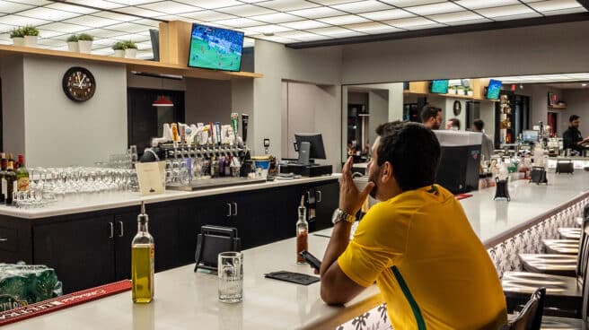 Una persona ve un partido en un bar mientras se bebe una cerveza