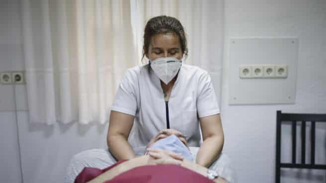 Una fisioterapeuta atiende a un paciente en una clínica.